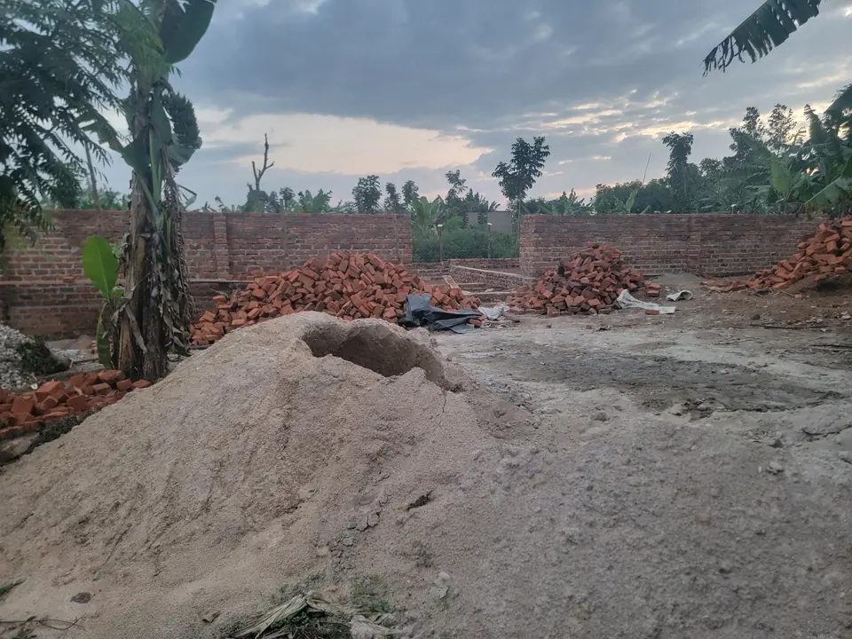 Brick walls of the boys&rsquo; dormitory rising on site, with piles of bricks and sand in front.