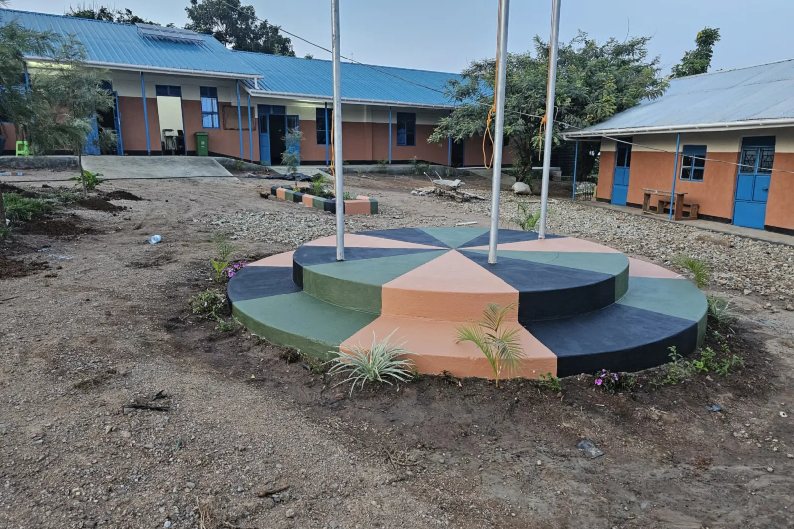 The Spectrum Secondary School compound, with a painted round platform, flagpoles and classroom blocks around a open yard.